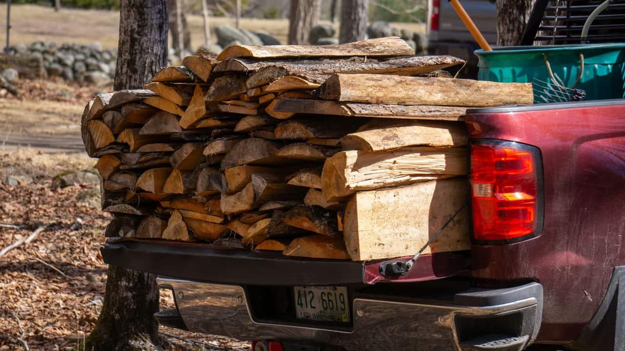 A pickup truck loaded with a full cord of split firewood, ready for delivery
