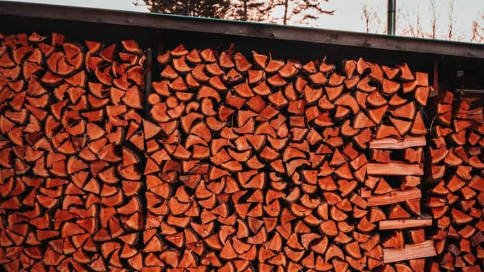 A large, neatly stacked cord of firewood stored outdoors for seasoning