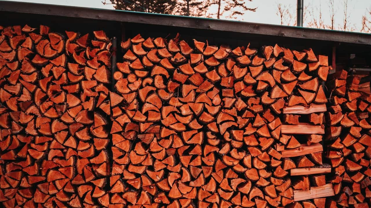 A large, neatly stacked cord of firewood stored outdoors for seasoning